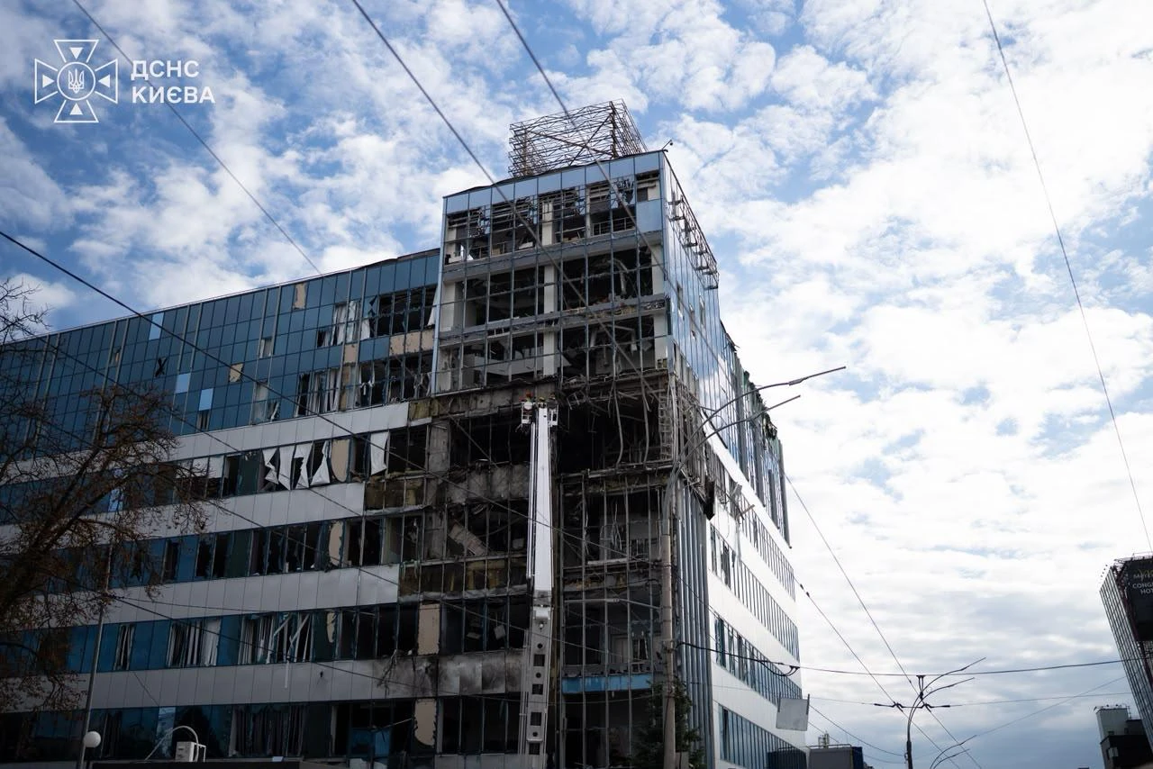 Пошкоджений фасад офісної будівлі в Солом'янському районі Києва, вибиті вікна та горівші авто на парковці після удару